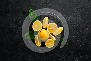 Fresh yellow sliced lemons on black stone background. Citrus fruits. Top view.