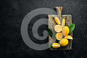 Fresh yellow sliced lemons on black stone background. Citrus fruits. Top view.