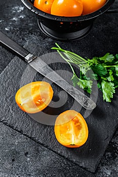 Fresh yellow tomato cut in half. Black background. Top view