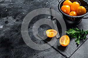 Fresh yellow tomato cut in half. Black background. Top view. Copy space