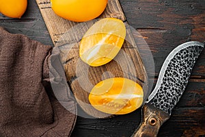 Fresh yellow tomatoes, on old dark  wooden table background, top view flat lay