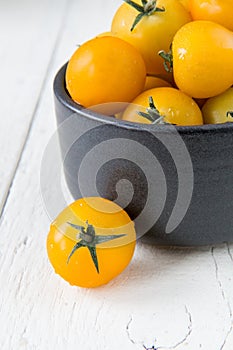 Fresh yellow tomatoes on white wooden table