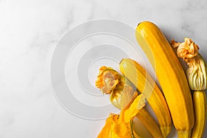 Fresh yellow zucchini or squash with flowers on white background. Top view with copy space.