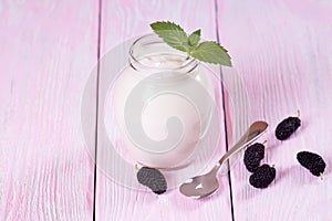 Fresh yogurt with mulberries in a glass jar.