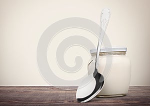 Fresh yogurt with spoon on table