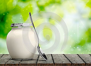 Fresh yogurt with spoon on table