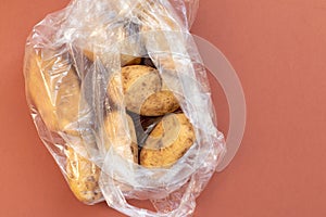 Fresh young potatoes in a plastic bag on brown background, zero waste and ecology pollution concept