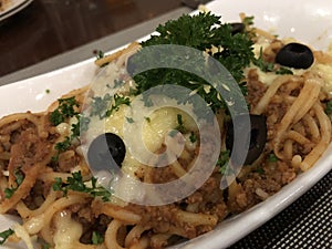 Fresh and yummy spaghetti with beef Bolognese sauce garnished with olives and parsley