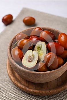 Fresh Ziziphus jujuba fruits in wooden bowl on table, closeup