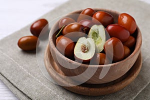 Fresh Ziziphus jujuba fruits in wooden bowl on table, closeup