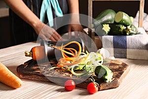 Fresh zucchini and carrot spaghetti with spiral grater on wooden table