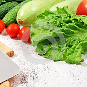 fresh zucchini, cucmber, tomato, lettuce and vegetables on gray background, healthy food concept