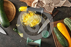 Fresh zucchini spaghetti with spiral grater and vegetables on dark table