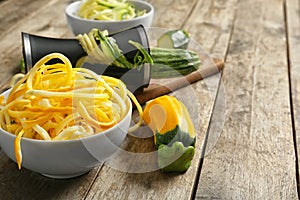 Fresh zucchini spaghetti with spiral grater on wooden table