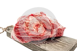 The freshest beef knuckle with bone lies on a wooden thick board on a light background. Close-up photo