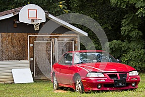 Freshly abandoned car in front of wood shed