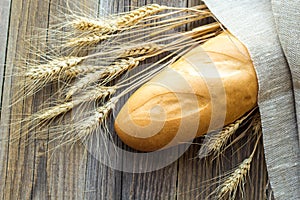 Freshly baguettes baked bread and wheat spikes on wooden background