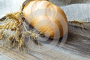 Freshly baguettes baked bread and wheat spikes on wooden background