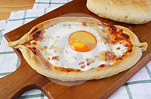 Freshly Baked Adjarian Khachapuri, Cheese and Egg Filled Georgian Bread on wooden Breadboard