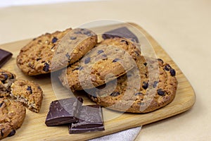 Freshly baked American chocolate chip cookies on rustic brown wooden table background.