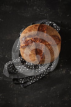 Freshly baked Artisan sourdough bread loaves with kitchen towel on black concrete backgroun