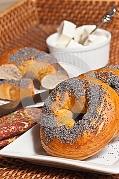 Freshly baked bagel with poppy seeds in a white rectangular plate