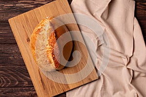 Freshly baked bread on a cutting board and dark kitchen table