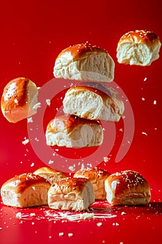 Freshly Baked Bread Loaves with Sesame Seeds Tumbling in Air on Vibrant Red Background