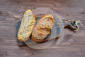 Freshly baked bread from wheat flour with sunflower seeds, pumpkin, sesame flat lay on aged wooden cooting board