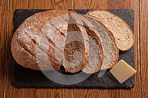 Freshly baked brown bread with butter on slate