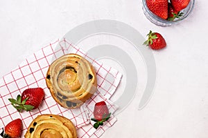 Freshly Baked Buns with Raisins and Cinnamon Decorated with Strawberry on Napkin Light Gray Background Horizontal Sweet Homemade