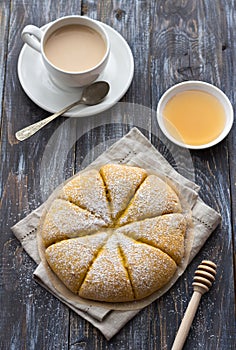 Freshly baked carrot scones with honey and cup of tea with milk on wooden background