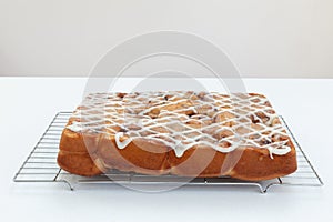 Freshly baked chelsea buns on a wire cooling rack and neutral ba