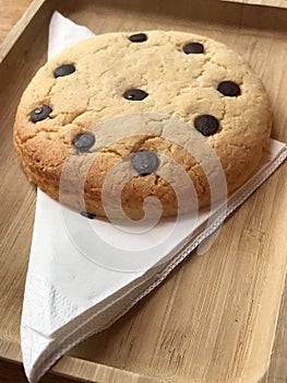 Freshly Baked Chocolate Chip Cookie in wooden plate with napkin.