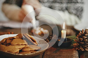 Freshly baked christmas gingerbread cookies in plate on background of rustic table with candle, spices, decorations. Moody image.