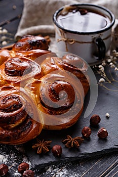 Freshly baked cinnamon buns with spices and stuffing with coffee drink on wooden table.
