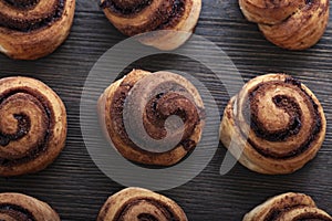 Freshly baked cinnamon rolls buns with spices on wood background. Christmas pastries. Close-up. Top view
