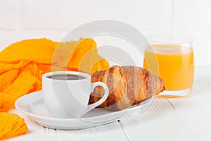 Freshly baked croissant orange juice, jam, cup of black coffee on white wooden background. French breakfast. Fresh pastries for mo