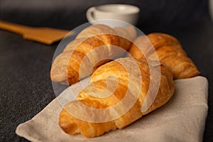 Freshly baked croissants on a black background with a white coffee cup,breakfast bread brown beverage morning,Concept: meal