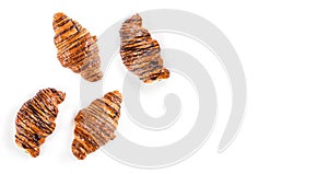 Freshly baked croissants decorated with chocolate sauce isolated on white background, top view