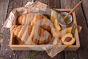 Freshly baked croissants with fruit jam, caramel and honey on wooden boards.