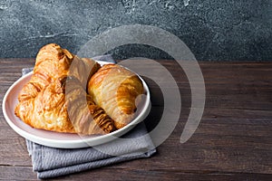 Freshly baked croissants on a plate, dark background, copy space