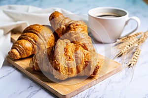 Freshly baked croissants on wooden cutting board with coffee