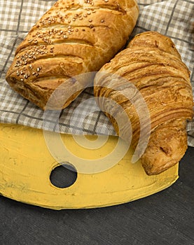 Freshly baked croissants on wooden cutting board, top view.