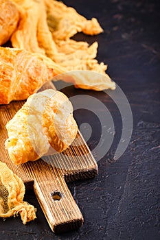 Freshly baked croissants on wooden cutting board, top view