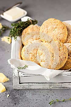 Freshly baked delicious homemade English scones with cheese and thyme on a light grey wooden tray.