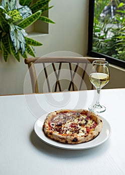 Freshly-baked delicious pizza with a glass of white wine on the table