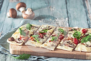 Freshly baked flammkuchen, traditional french tarte flambee or german pizza in a vegetarian recipe with mushrooms, cream cheese,