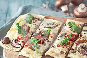 Freshly baked flammkuchen, traditional french tarte flambee or german pizza in a vegetarian recipe with mushrooms, cream cheese,