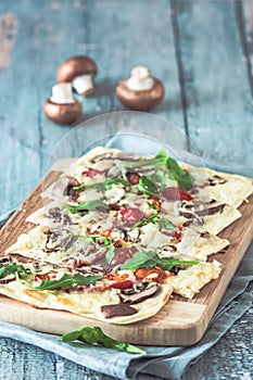 Freshly baked flammkuchen, traditional french tarte flambee or german pizza in a vegetarian recipe with mushrooms, cream cheese,